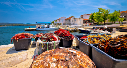 Terras aan een kleine haven met bootjes en blauwe zee in Kroatië