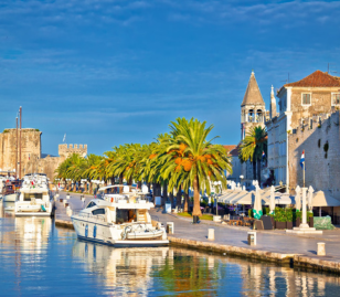 Boulevard van Trogir met palmbomen, boten en historische gebouwen