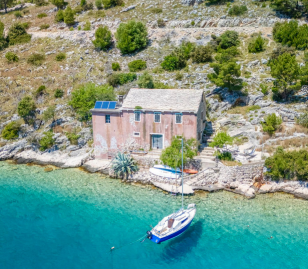 Natuurstenen huis aan een rustige baai met helderblauw water in Kroatië