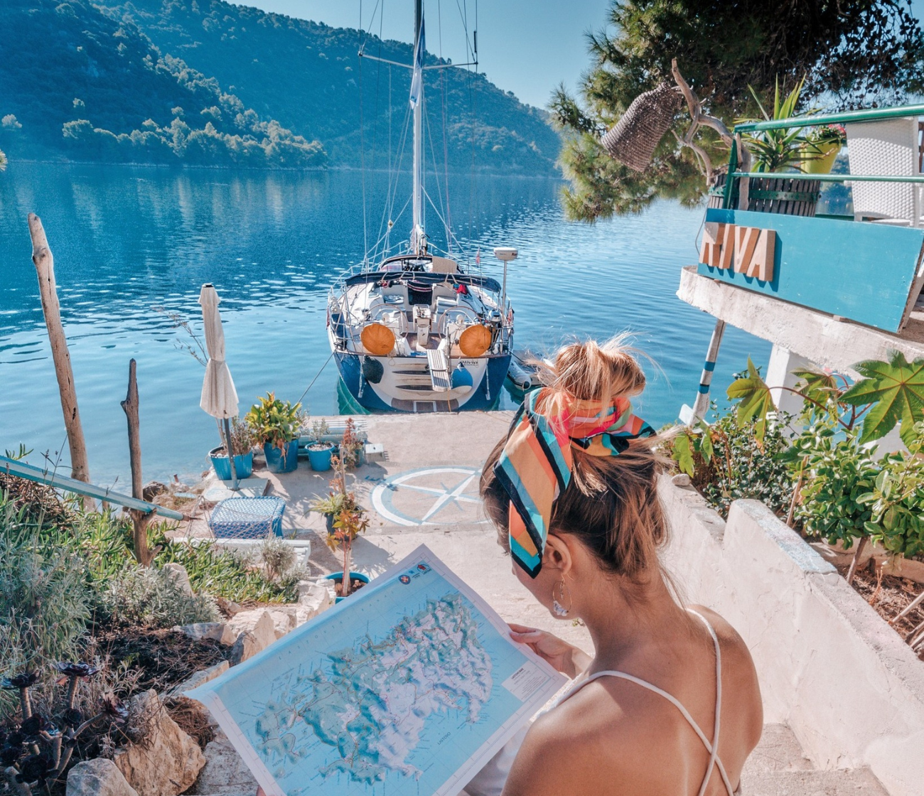 Vrouw bekijkt een kaart bij een zeilboot in een rustige baai in Kroatië