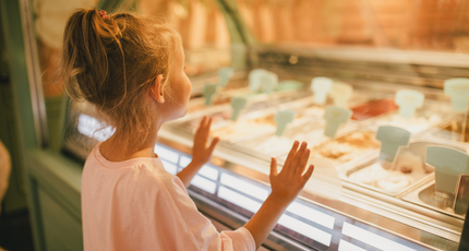 Jong meisje kijkt nieuwsgierig in een vitrine met ijs tijdens een vakantie in Kroatië