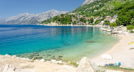 Rustige baai met kiezelstrand en bergen in Kroatië