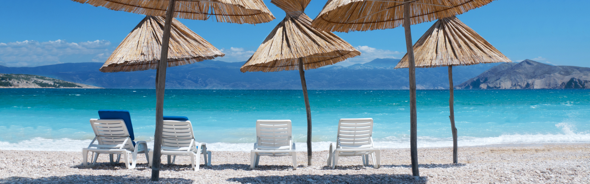 Strand met parasols en helderblauwe zee op eiland Krk