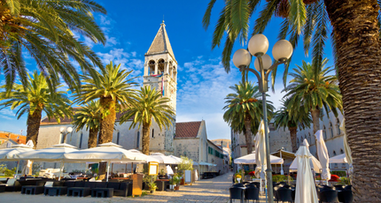 Mediterrane boulevard met palmbomen en kerktoren in het historische centrum van Trogir in Kroatië