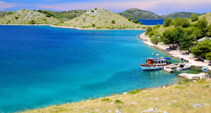 Turquoise baai met boot en rotsachtige eilanden aan de Dalmatische kust